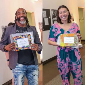 On the left Keiko Budech wears a teal and pink jumpsuit as she stands and holds a colorful frame with her alumni award certificate. Budech has straight shoulder-length brown hair. On the right Sekou Andrews wears a gray jacket over a black T-shirt and faded jeans with various words and patterns written in blue and black ink. He stands and holds a colorful frame with his alumni award certificate. Andrews has shoulder-length dark brown hair and a beard with dark brown and gray hair.